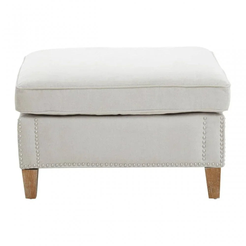 Beige fabric ottoman with cushioned top, wooden legs, and studded trim detail front view