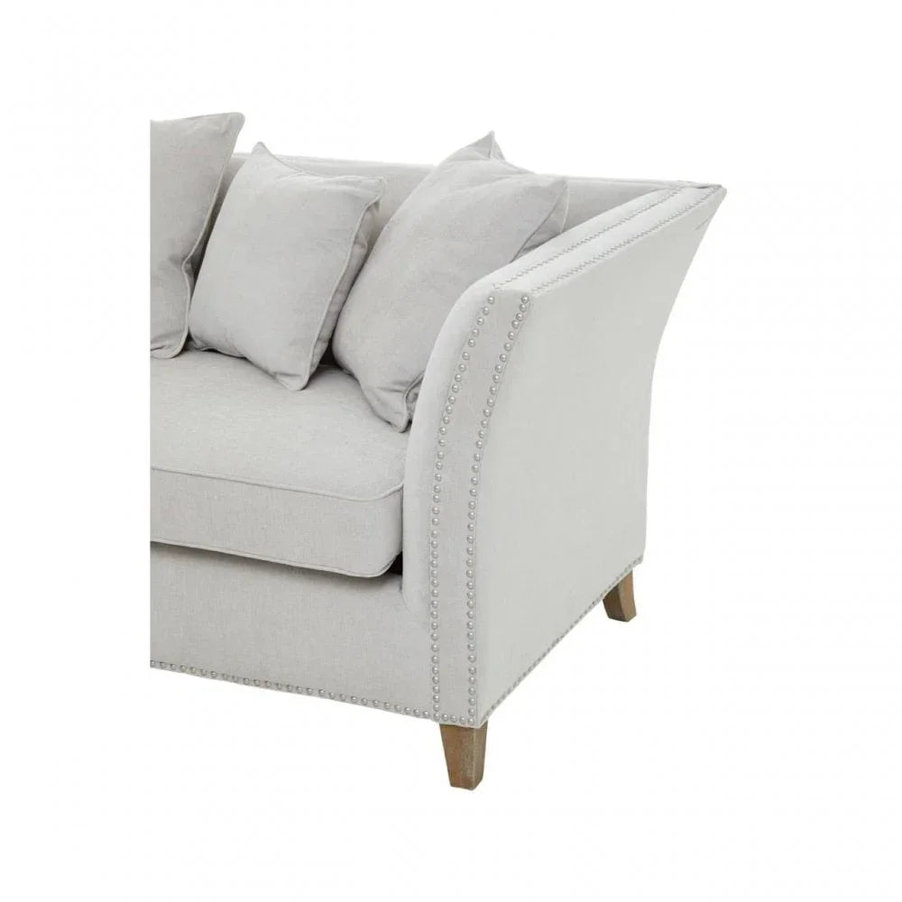 Light grey fabric sofa with nailhead trim and wooden legs, close-up of arm and cushions