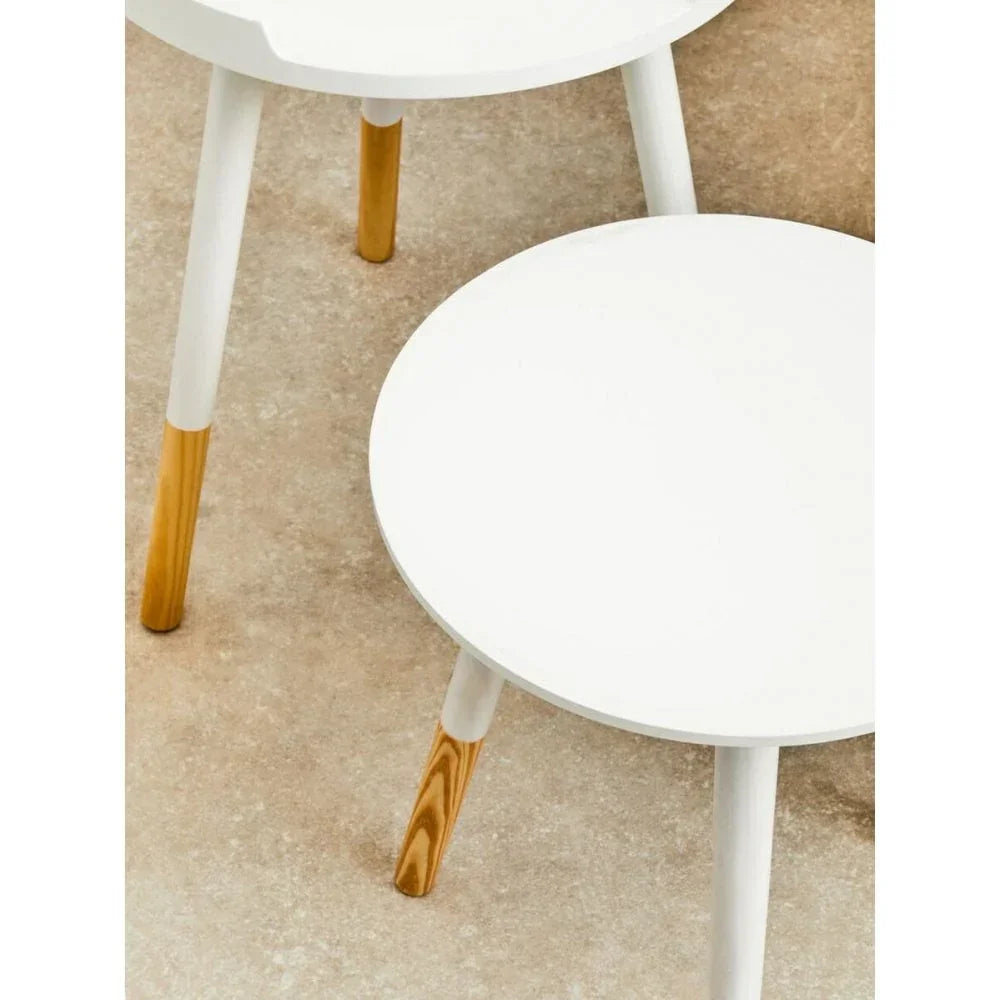 White round side tables with wood-effect legs on beige floor, close-up top view