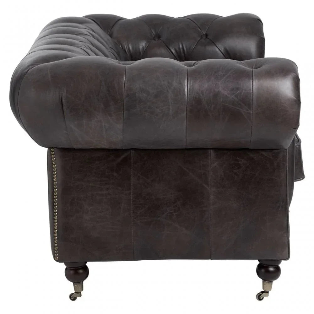 Brown leather Chesterfield sofa side view with button tufting and wooden caster legs