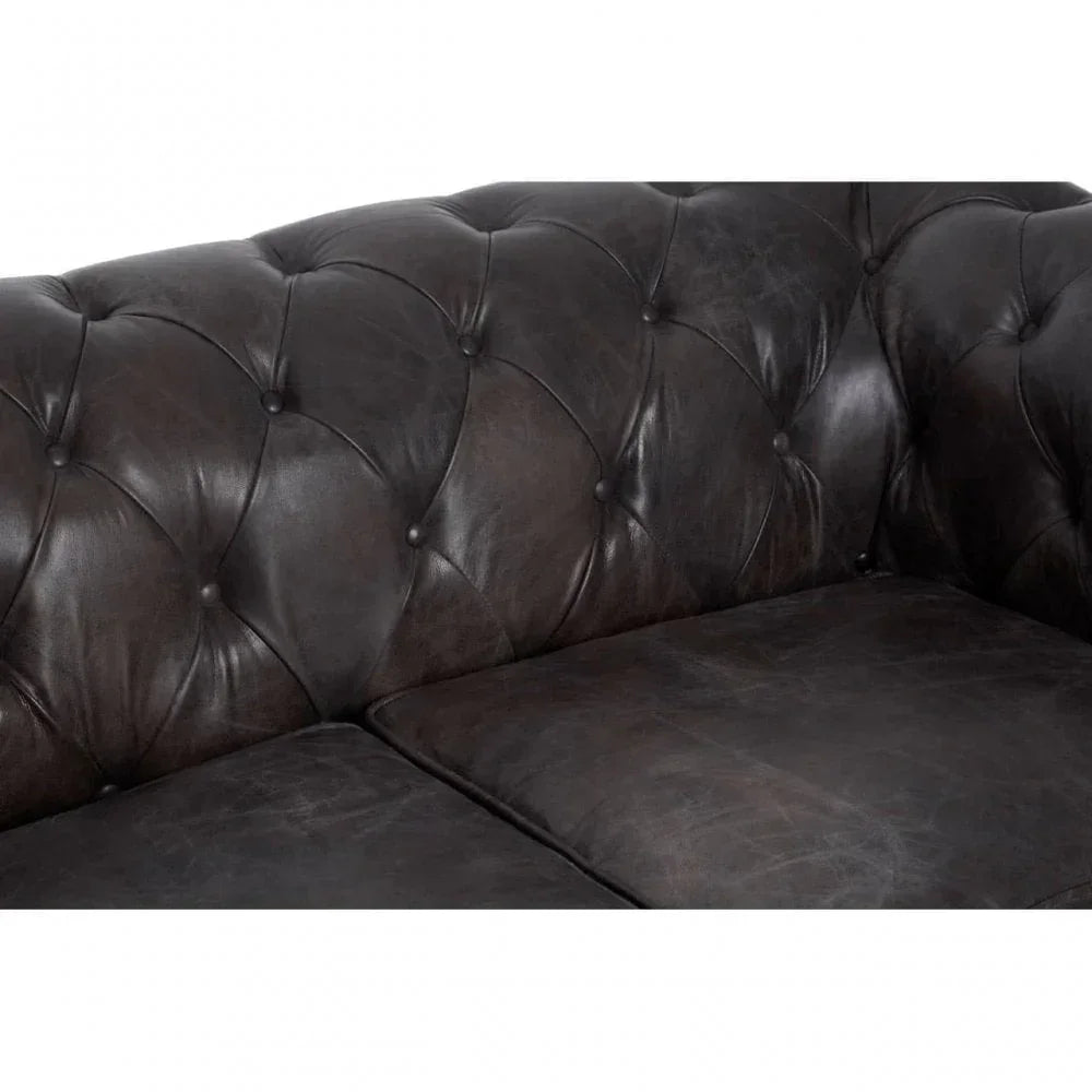 Dark brown leather sofa with tufted backrest and seat cushions, close-up view
