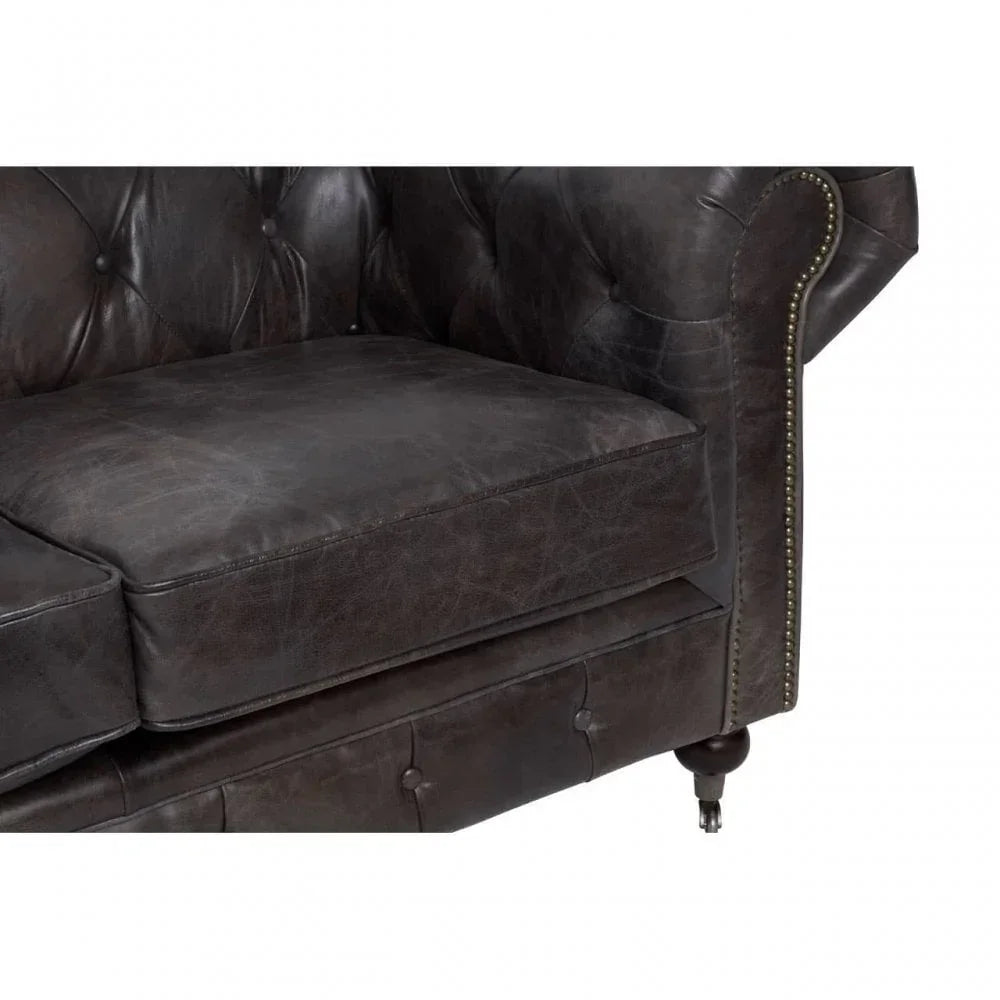 Dark brown leather sofa closeup with button tufting and brass stud detailing
