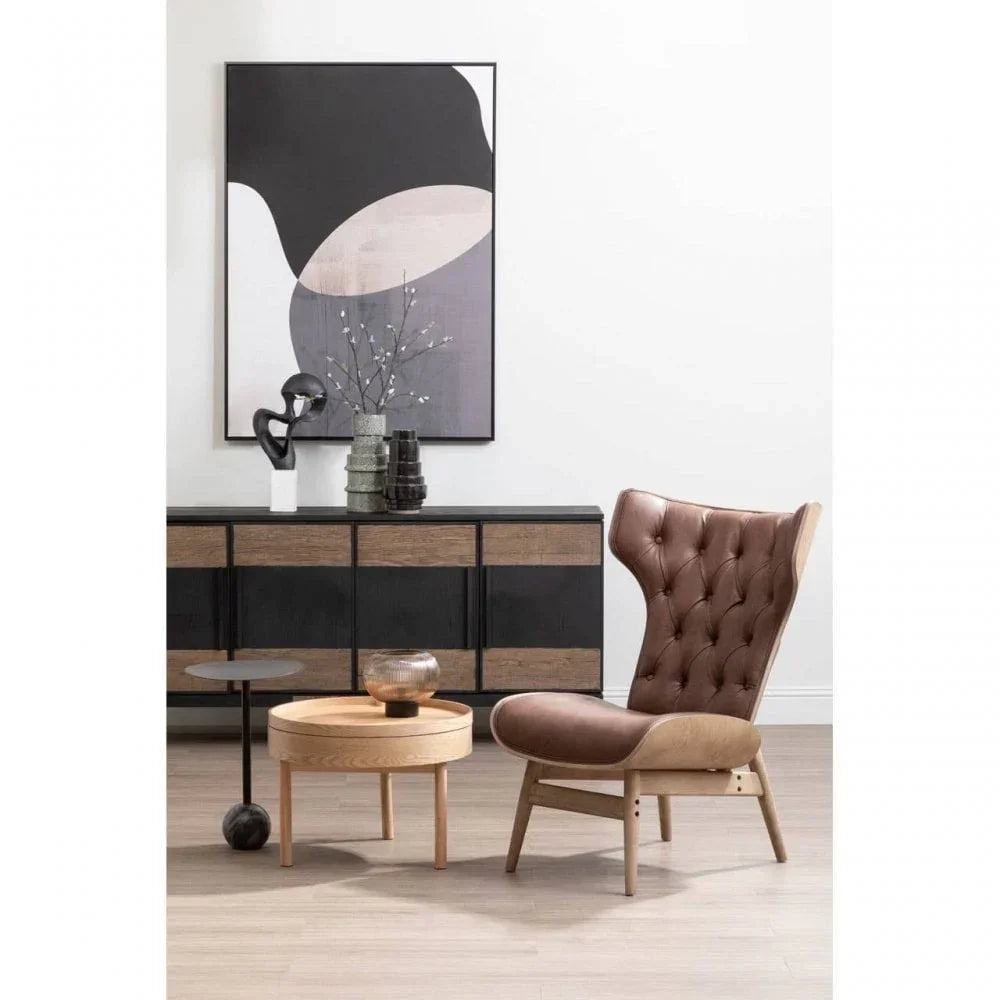 Brown leather accent chair with tufted back beside wood coffee table and black sideboard