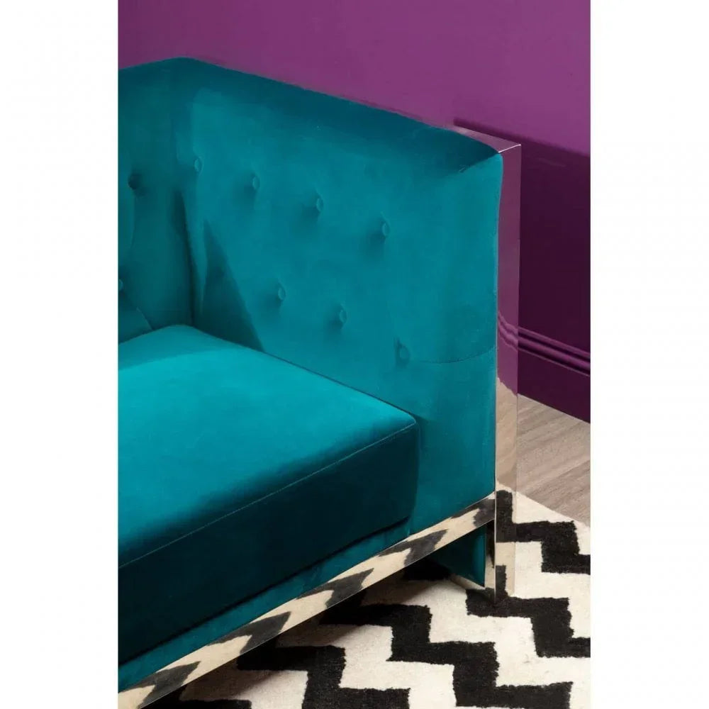 Teal velvet sofa corner with tufted back and chrome legs on geometric rug