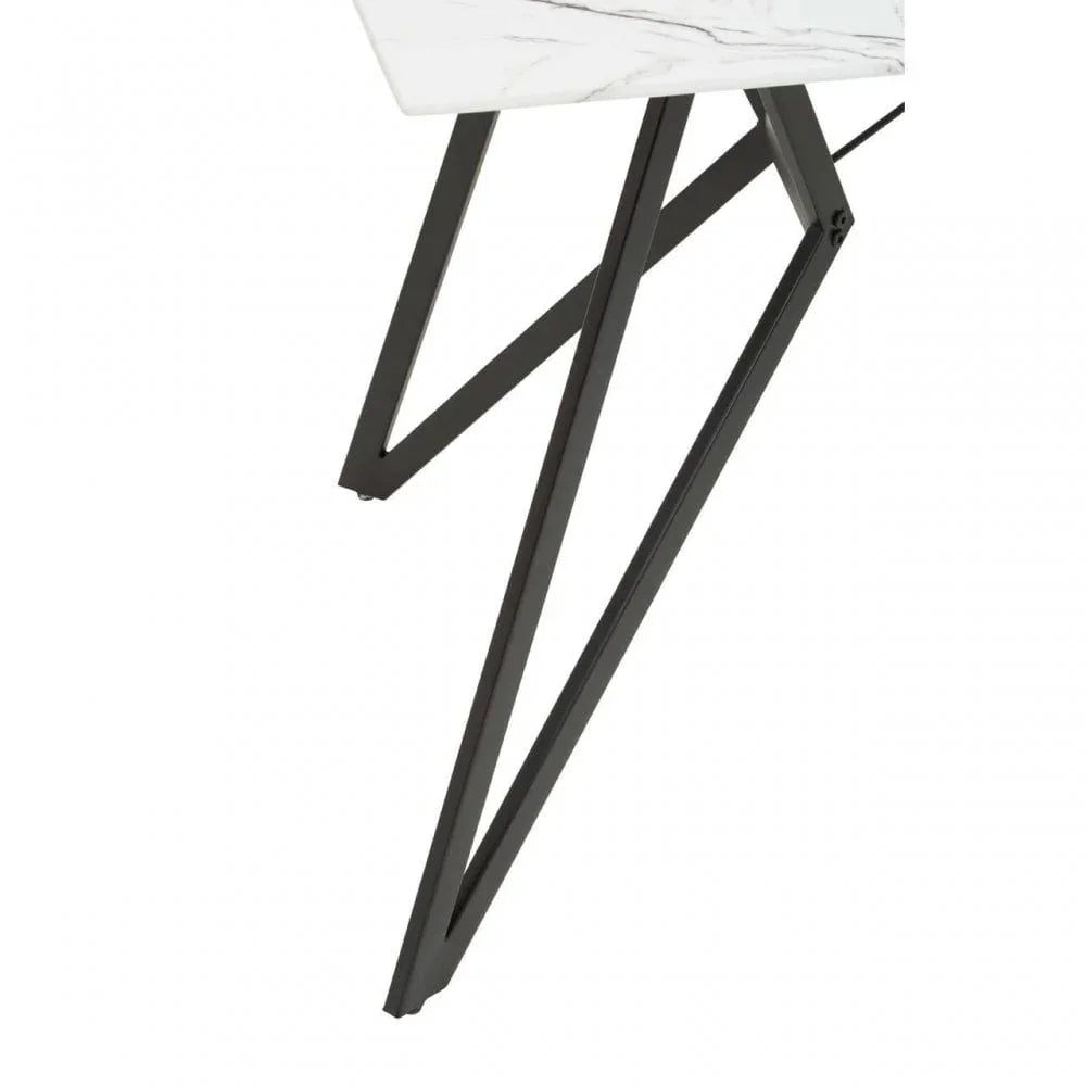 Modern dining table with white marble top and black metal angled legs, close-up view