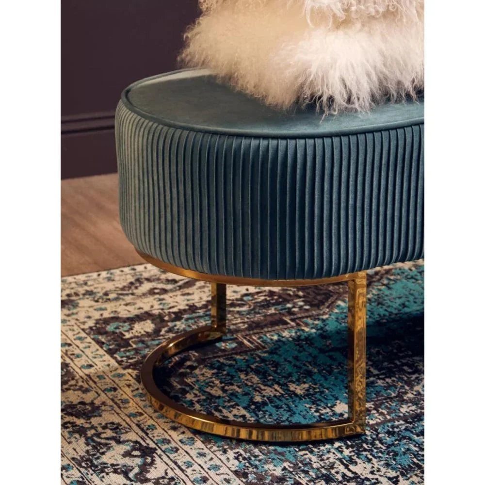 Teal velvet ottoman with gold metal base on patterned rug