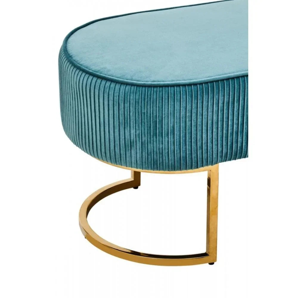 Blue velvet ottoman with gold circular metal base, vertical tufted sides, close side view
