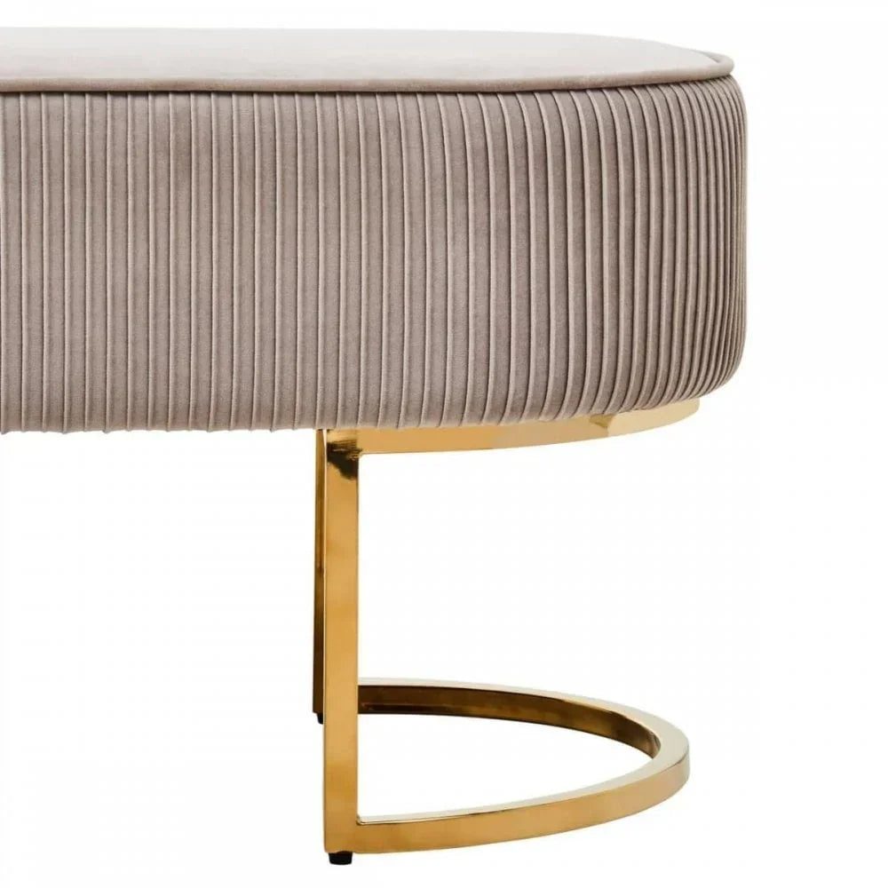 Beige velvet ottoman with gold metal base, close-up on curved leg and ribbed fabric detail