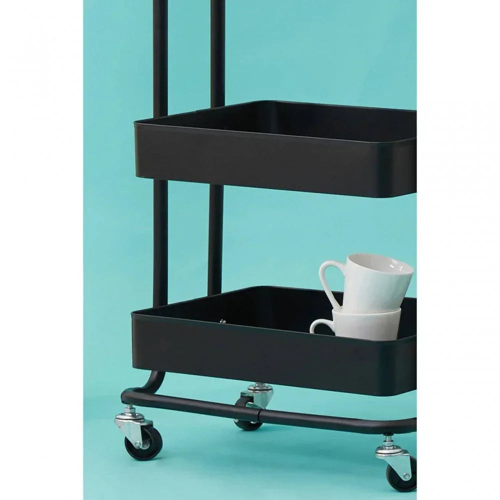 Black metal storage trolley with two tiers and white mugs on lower shelf, turquoise background
