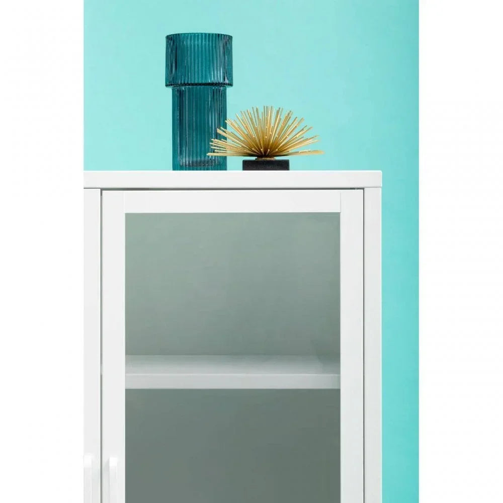White gloss cabinet with glass door, blue glass vase and gold decor on top, aqua background