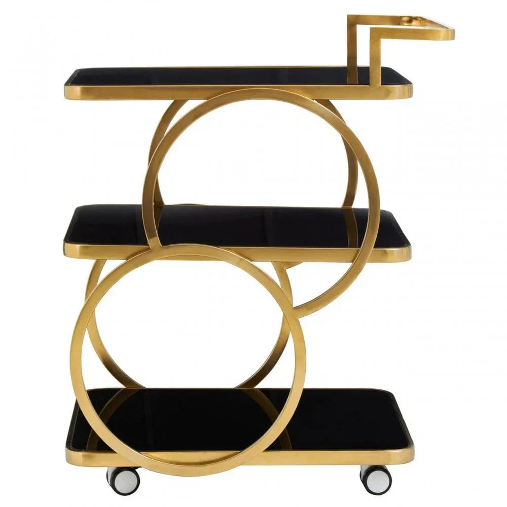Gold and black bar cart with three glass shelves and circular metal frame on wheels