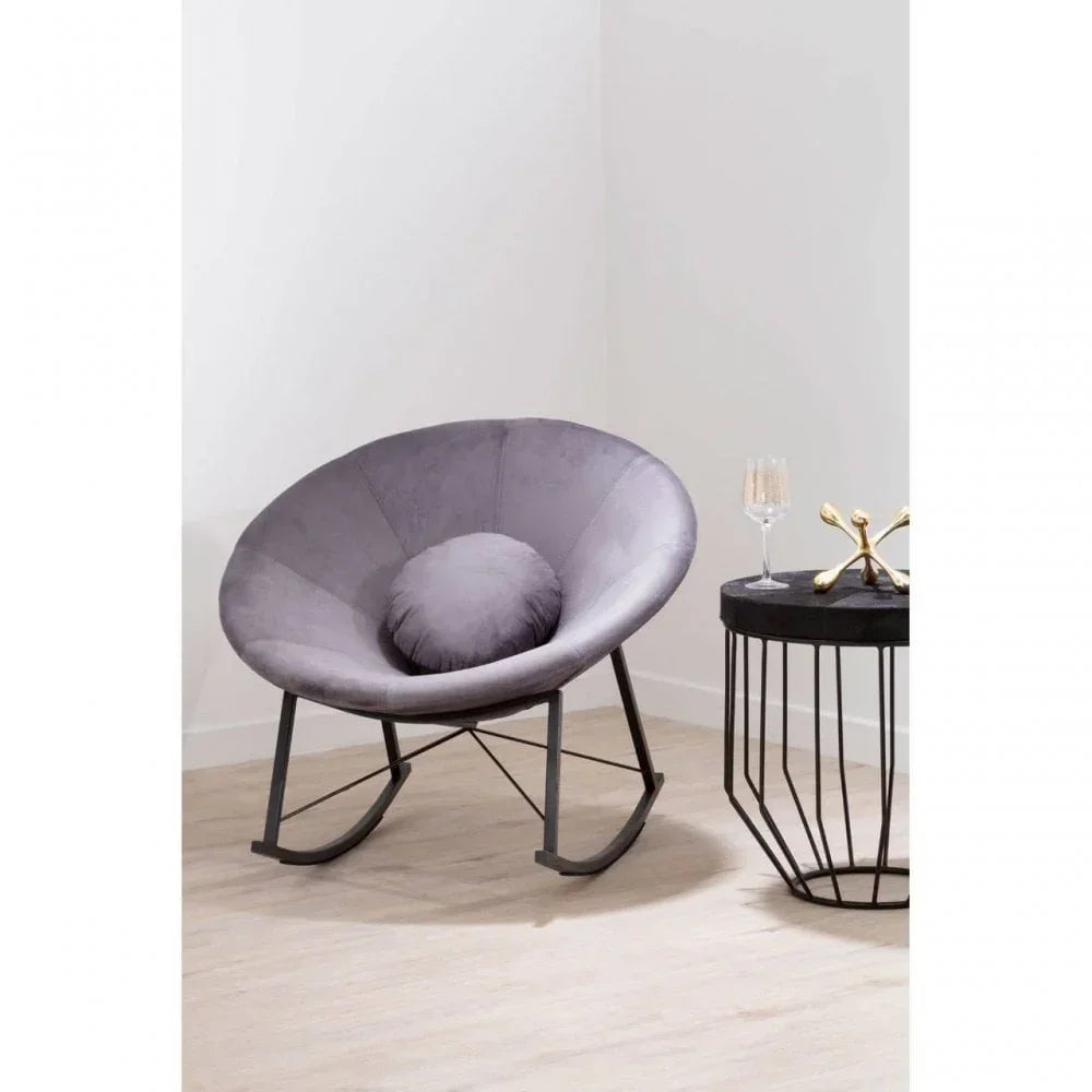 Grey fabric accent chair with circular cushion beside black metal side table