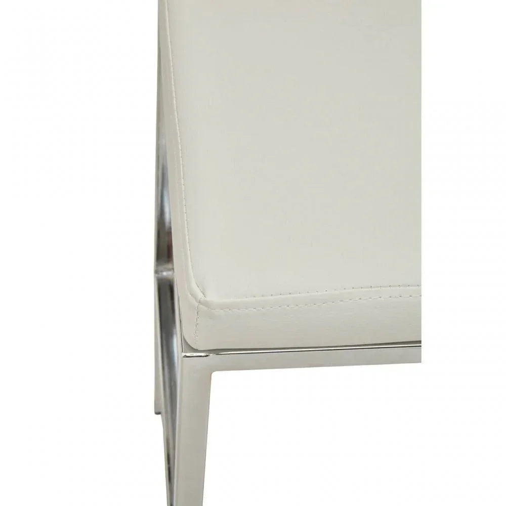 Close-up of cream dining chair with chrome metal legs and faux leather upholstery