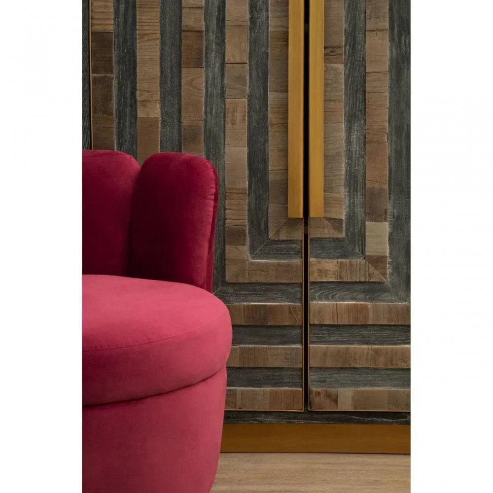 Pink velvet accent chair beside geometric wood cabinet with gold handles