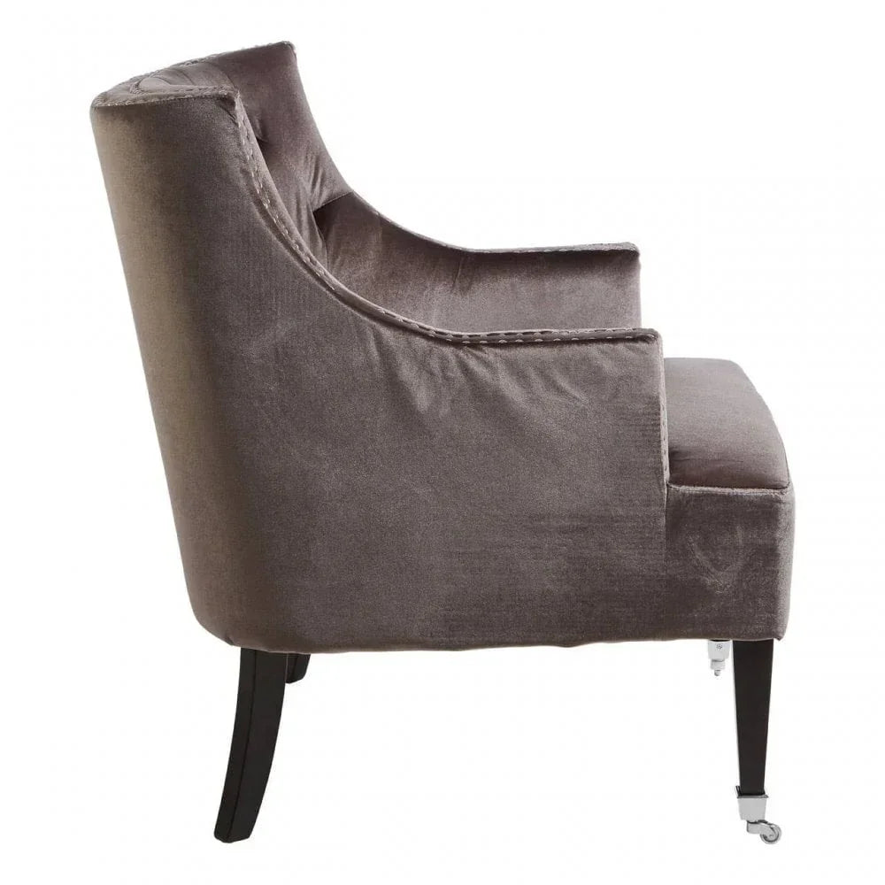 Side view of grey velvet accent chair with dark wood legs and front casters