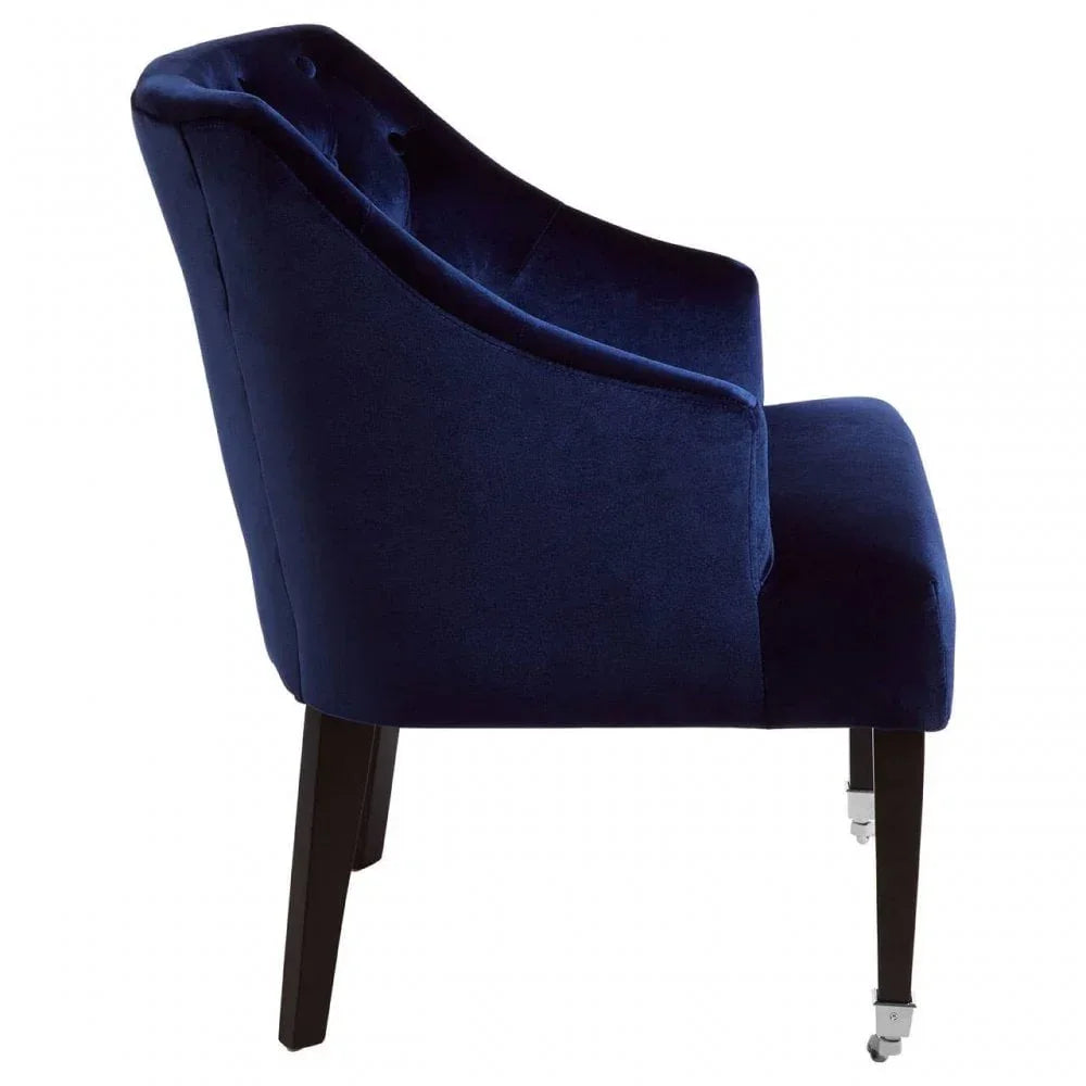 Side view navy velvet accent chair with tufted back and dark wooden legs on castors