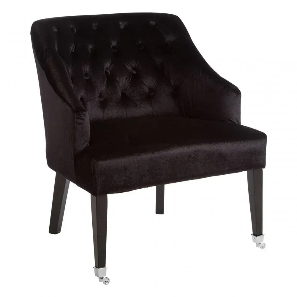 Black velvet accent chair with button-tufted back and dark wooden legs on castors