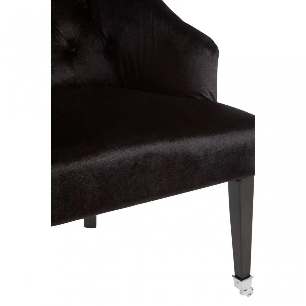 Close-up of black velvet armchair seat with dark tapered legs and chrome castor