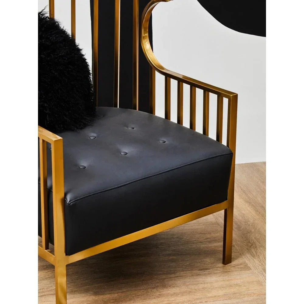 Black leather accent chair with gold metal frame and button tufted seat on wood floor