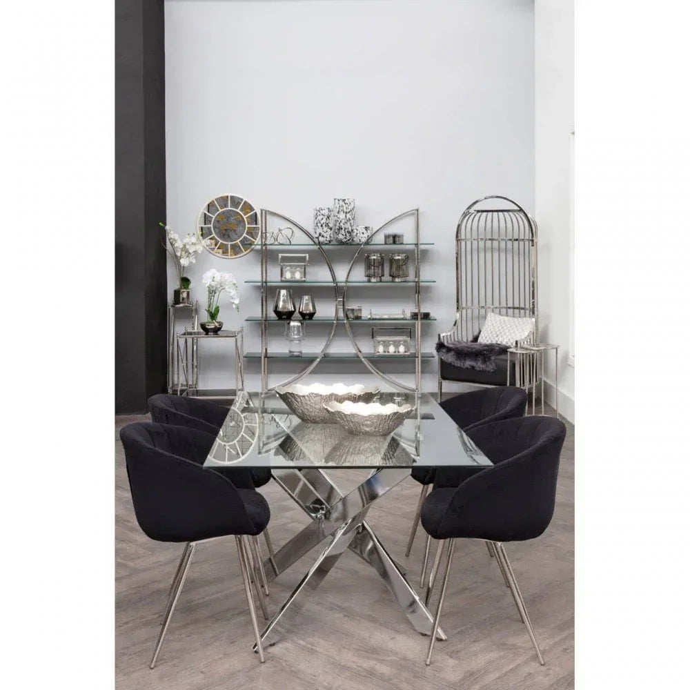 Glass dining table with chrome legs and four black velvet chairs in modern room setting
