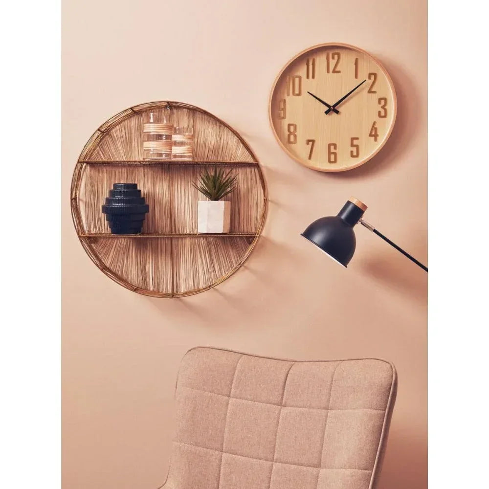 Round rattan wall shelf with decor, wooden wall clock, black desk lamp, and beige chair