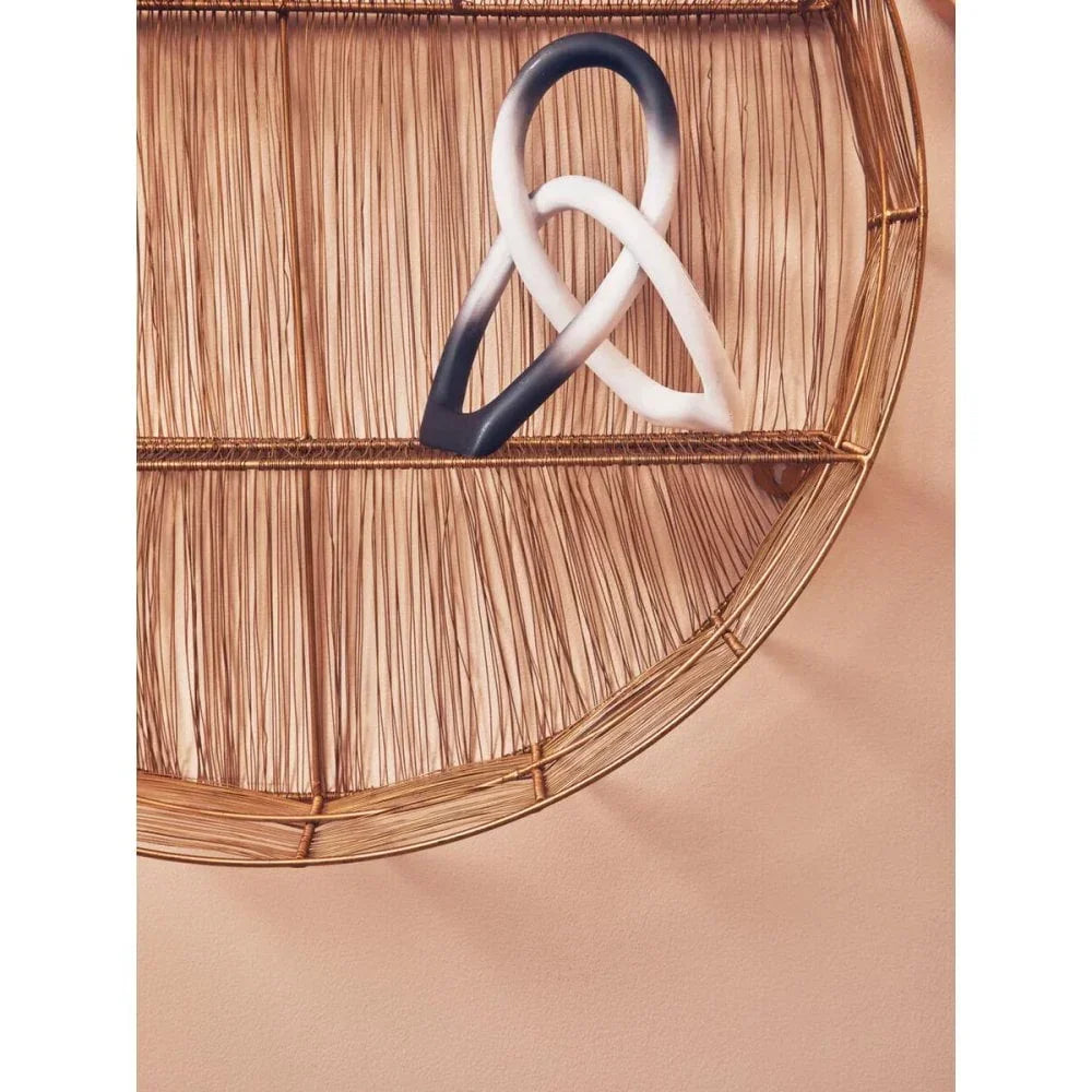 Half round rattan wall shelf with decorative black and white ceramic knot ornament