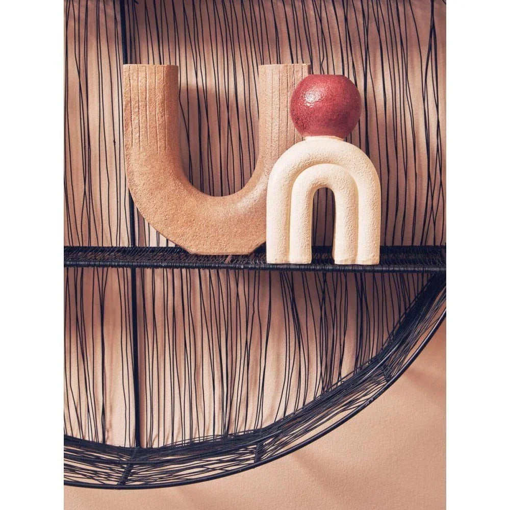 Ceramic decorative sculpture with U-shaped and arch forms on a black wire shelf