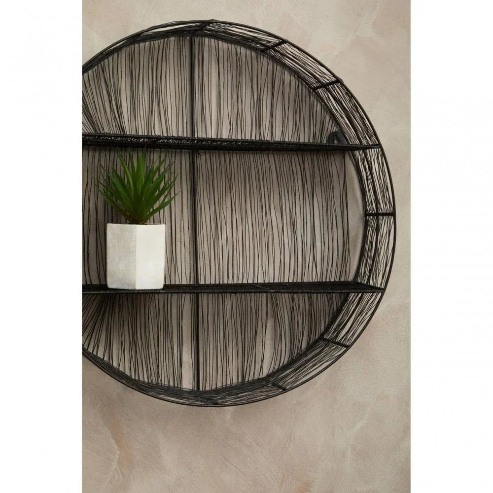 Round black wire wall shelf with potted plant on beige textured wall