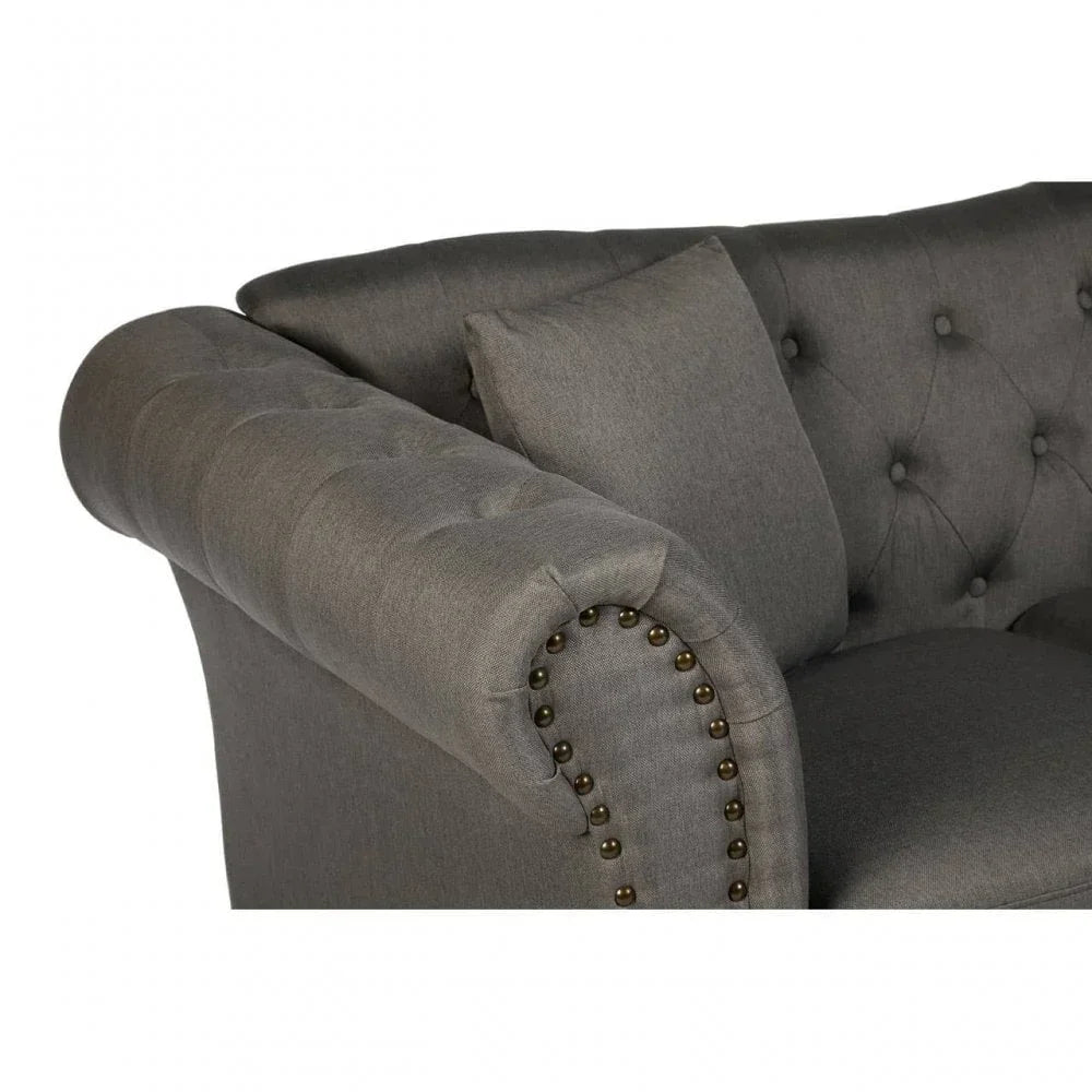 Close up of grey fabric sofa with button-tufted back and studded rolled armrest