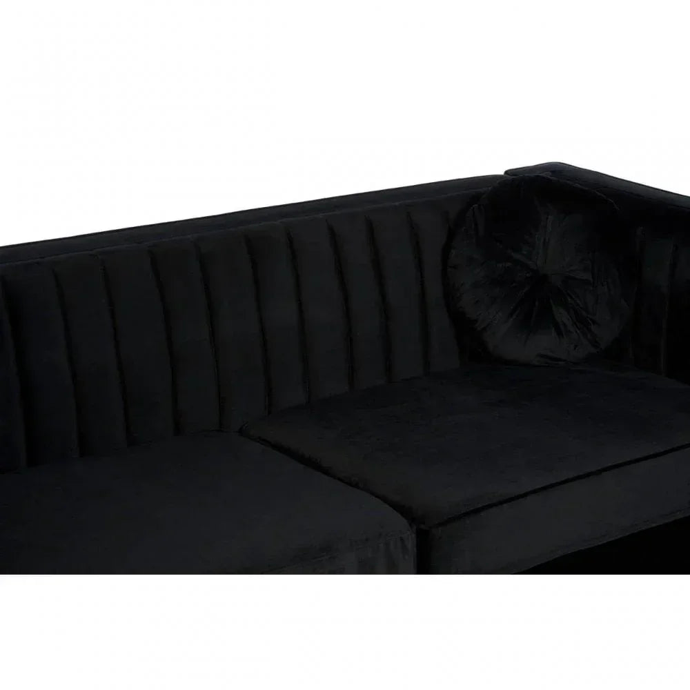 Black velvet sofa with vertical stitched backrest and round cushion, corner detail view