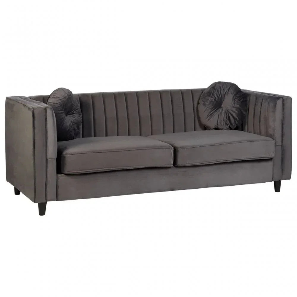 Grey velvet sofa with channel-tufted back and two round cushions on black legs