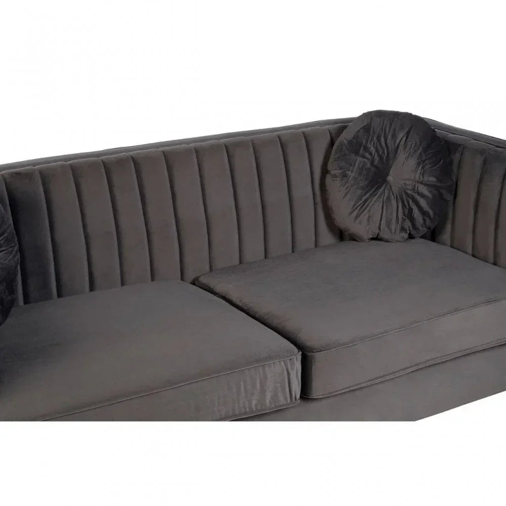 Dark grey velvet sofa with vertical channel tufting and round cushion, close-up view