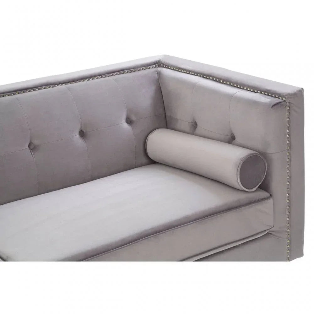 Grey velvet sofa with button-tufted back, silver stud trim, and matching bolster cushion