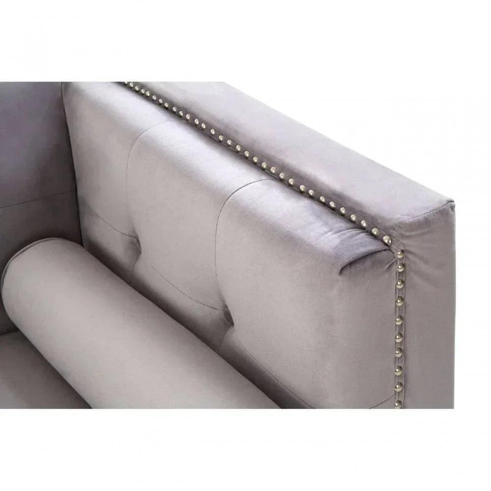Grey velvet sofa with button-tufted backrest and silver stud detailing, corner view
