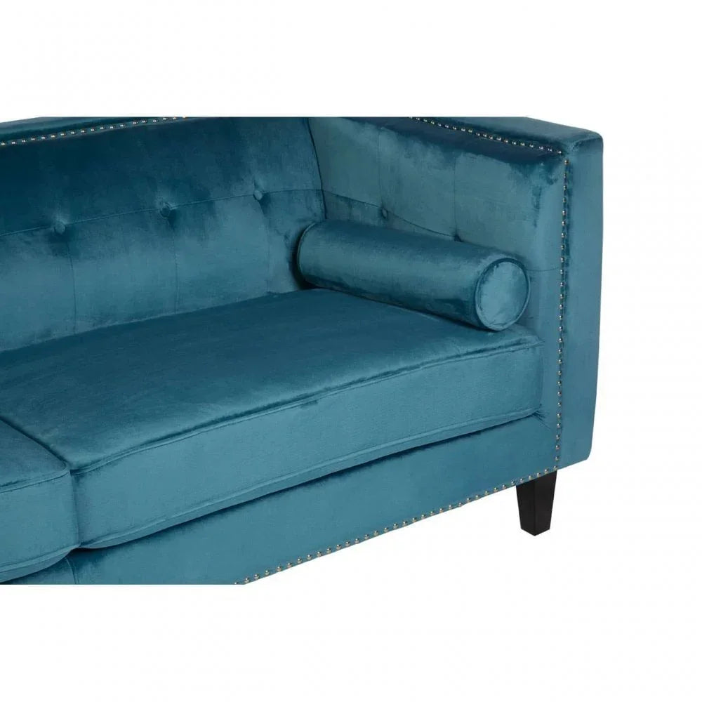 Blue velvet sofa with tufted backrest, silver stud trim, and matching bolster cushion