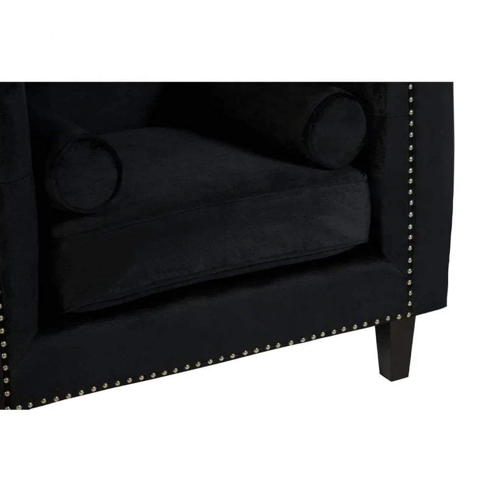 Black velvet sofa corner with studded trim and bolster cushion detail