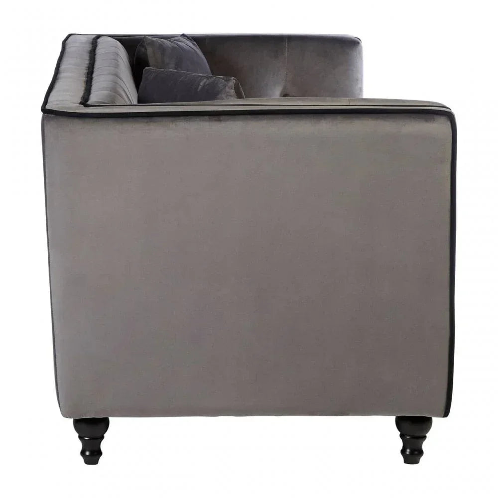 Side view of grey velvet sofa with black piping and turned wooden legs
