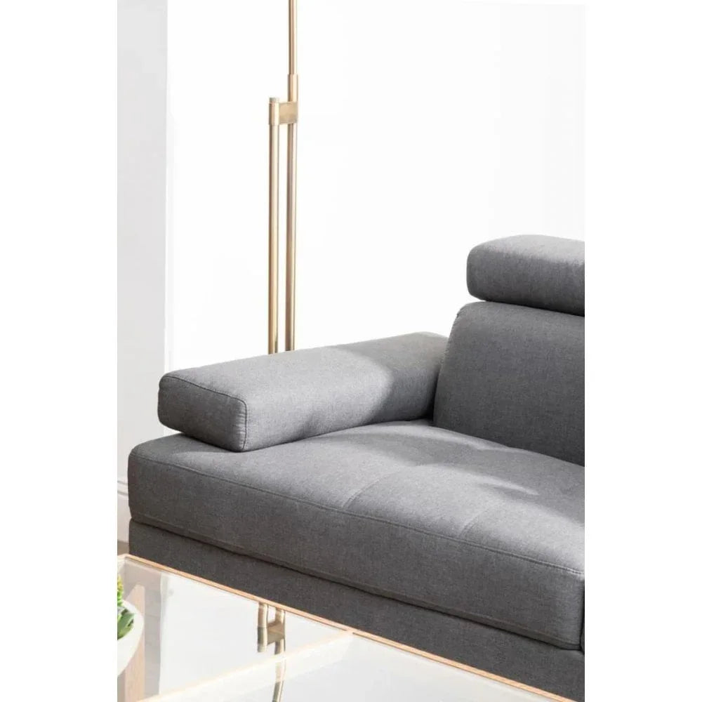 Grey fabric sofa armrest and adjustable headrest beside gold floor lamp
