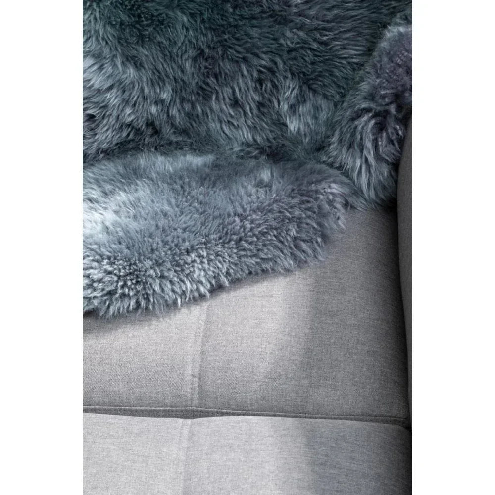 Grey sheepskin rug draped over light grey fabric sofa cushion