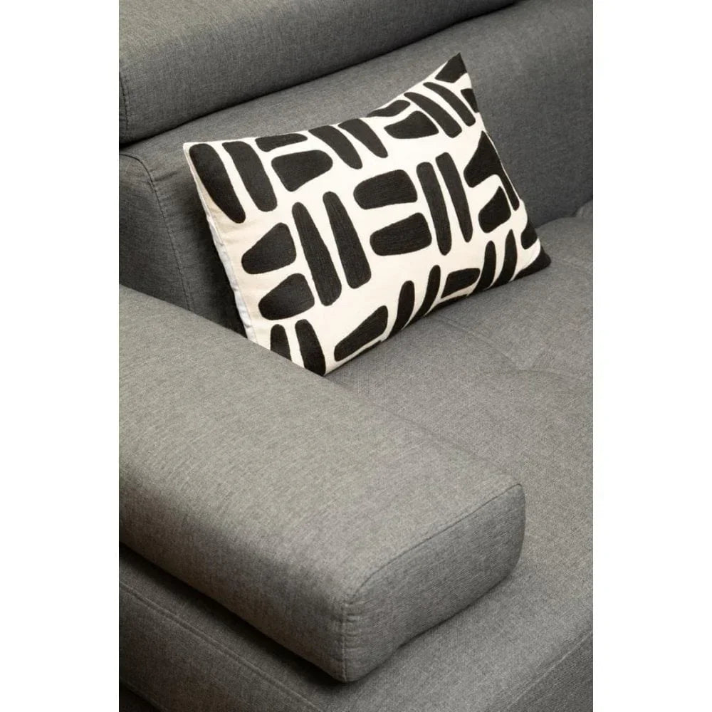Black and white patterned cushion on grey fabric sofa armrest