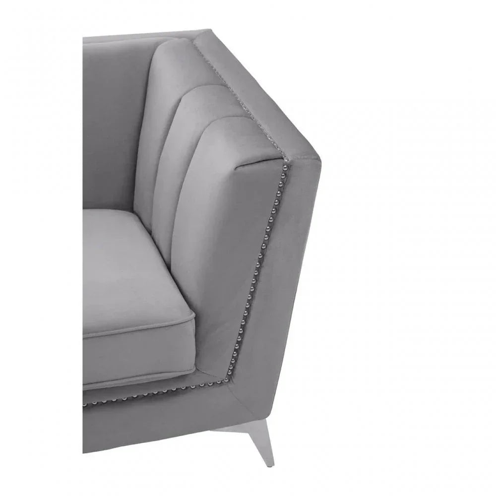 Grey velvet sofa corner with vertical tufting and silver nailhead trim detail