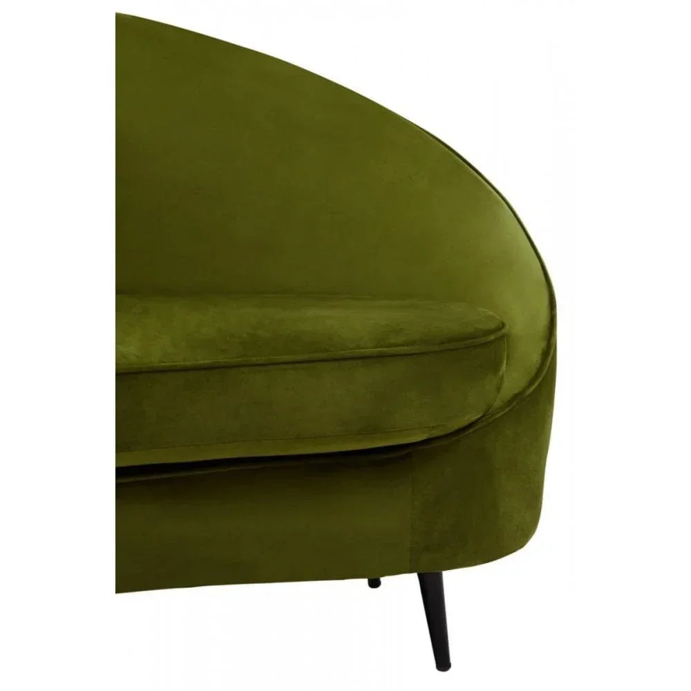Green velvet sofa curved backrest and seat cushion with black tapered leg closeup
