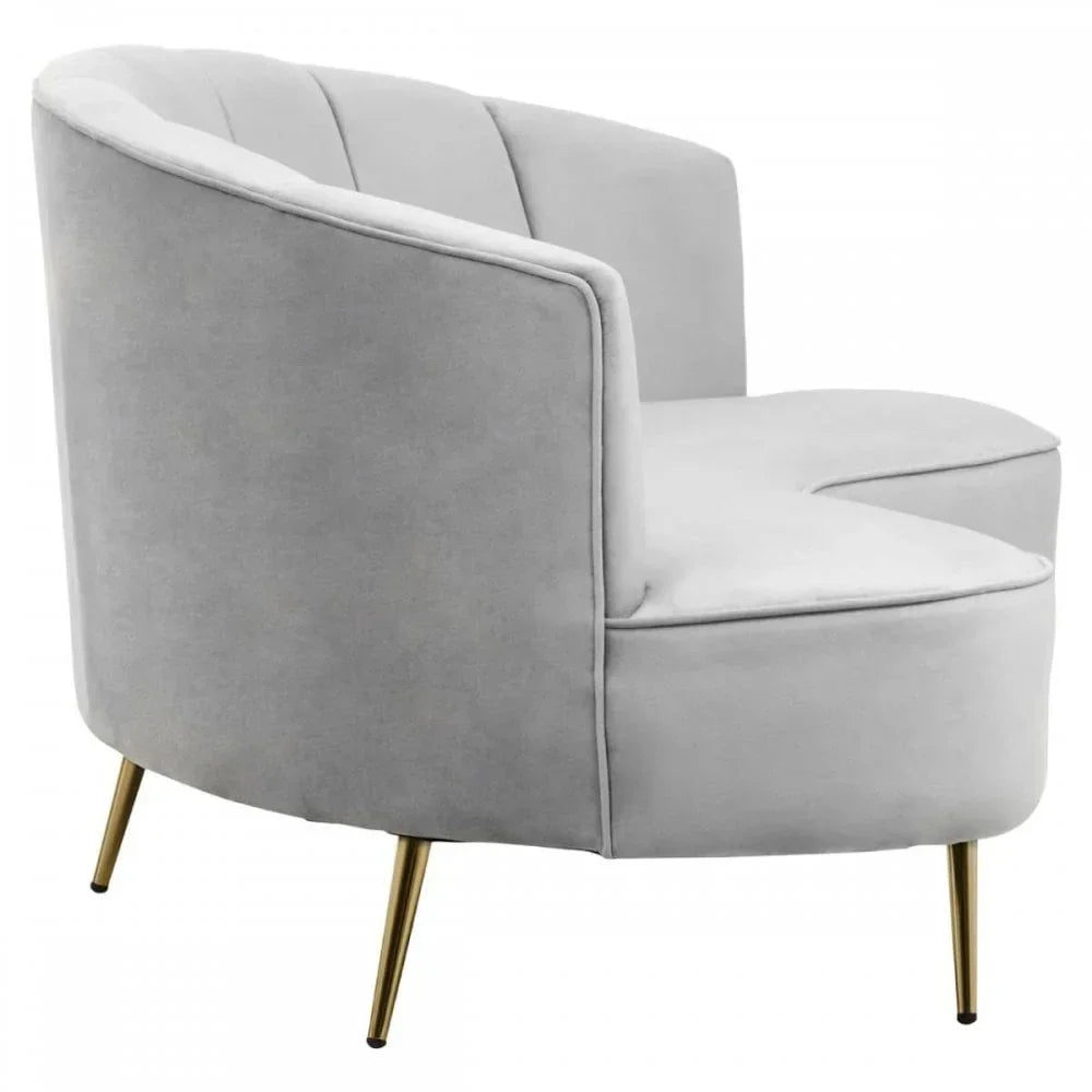 Light grey velvet accent chair with curved back and gold metal legs, side angle view