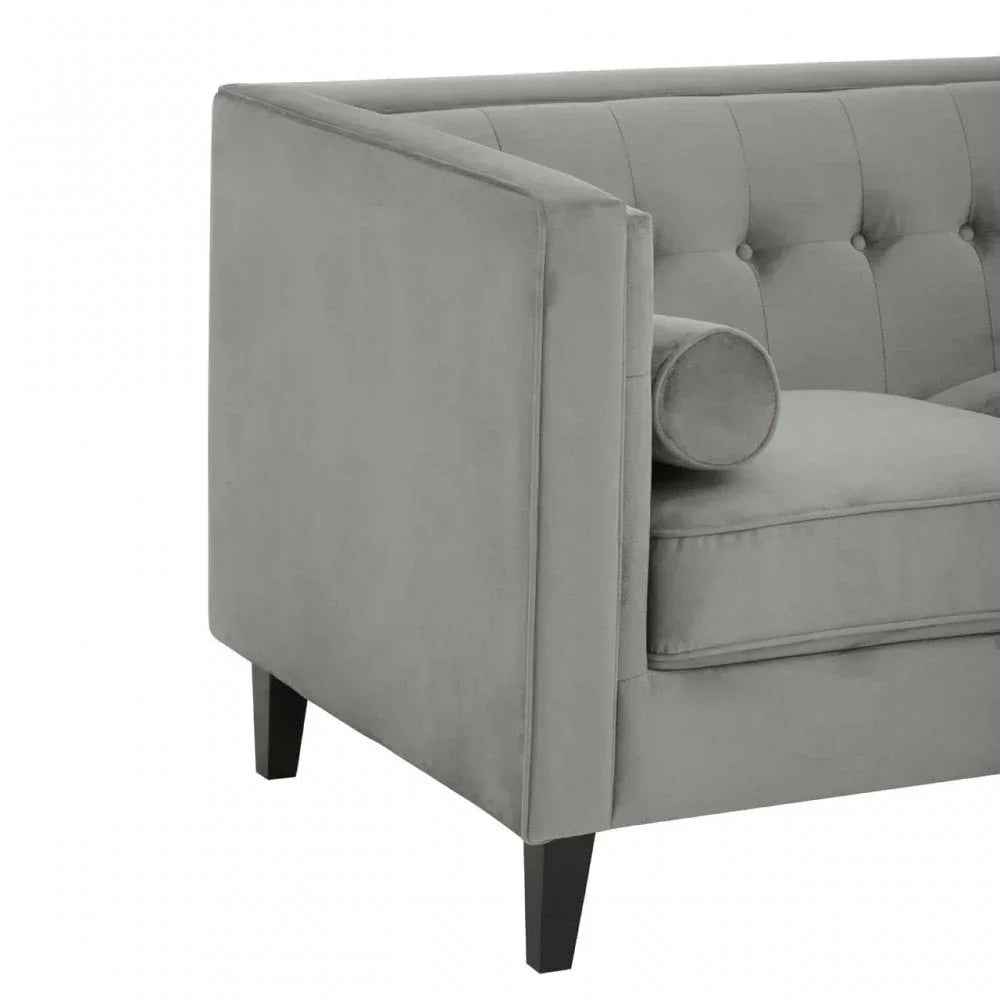 Grey velvet sofa with tufted backrest and matching bolster cushion, angled view
