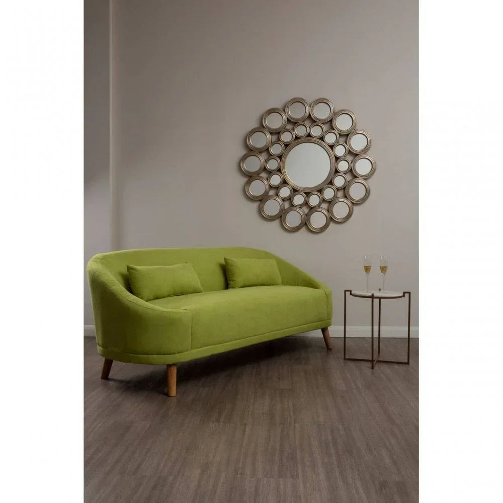 Green fabric sofa with wooden legs, circular mirror on wall, small table with glasses