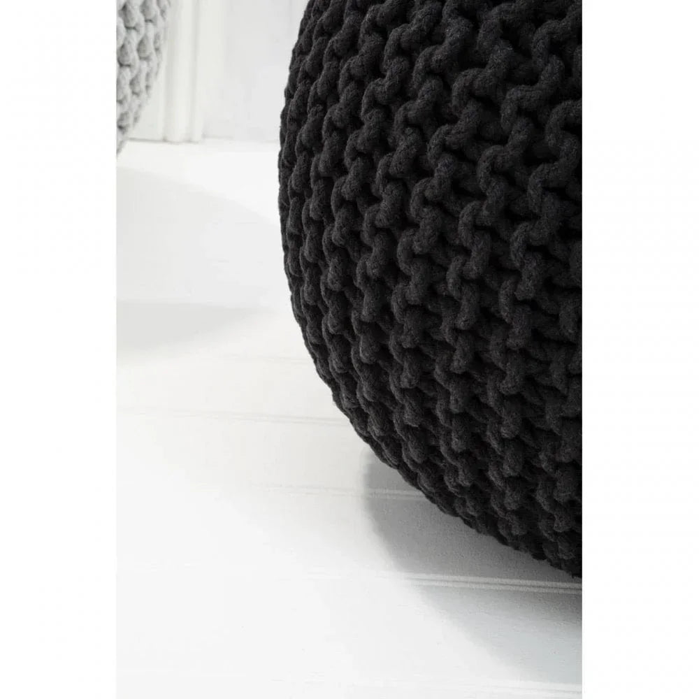 close up of black knitted pouffe with chunky textured pattern on white wooden floor