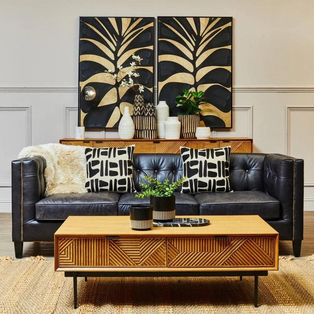 Black leather sofa with patterned cushions and geometric wood coffee table in modern living room