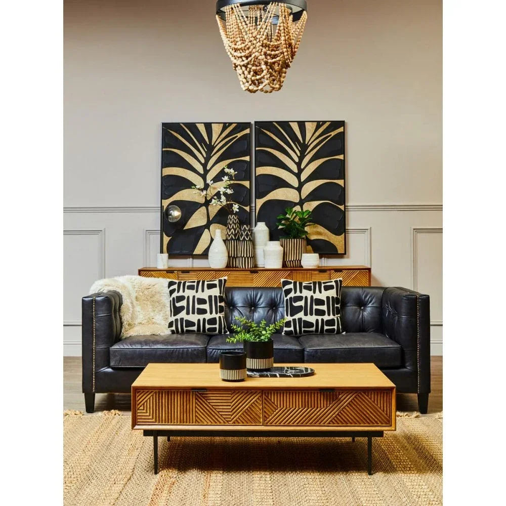 Black leather sofa with patterned cushions and wooden coffee table in modern living room