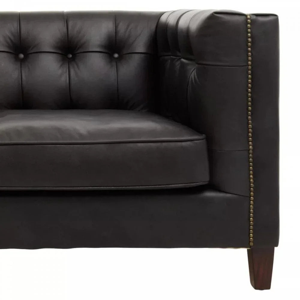 Black leather sofa corner with button tufting and brass stud detail