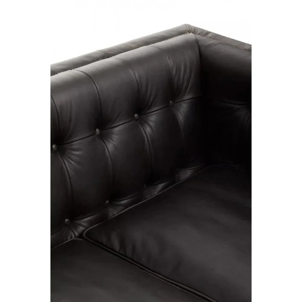 Close-up of black leather sofa corner with tufted backrest and seat cushion